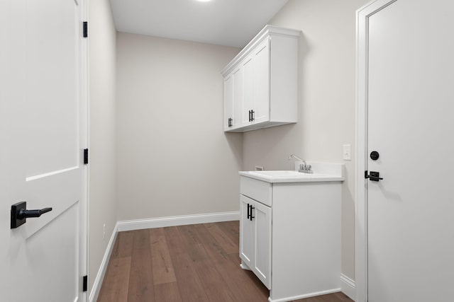 clothes washing area with hardwood / wood-style floors and sink