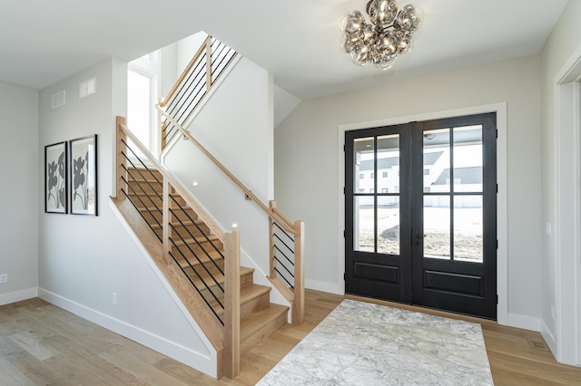 entryway featuring french doors, light wood-style floors, and stairs