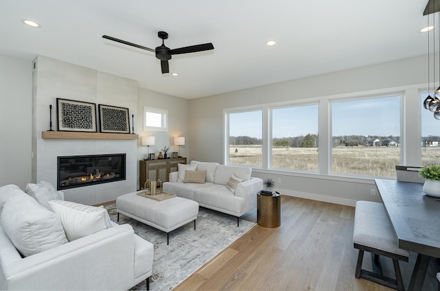 living area with light wood-style flooring, recessed lighting, baseboards, ceiling fan, and a tile fireplace