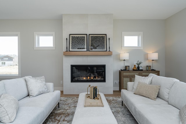 living area with a fireplace, baseboards, and wood finished floors