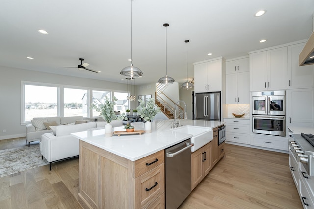 kitchen featuring open floor plan, light wood-type flooring, recessed lighting, appliances with stainless steel finishes, and a sink