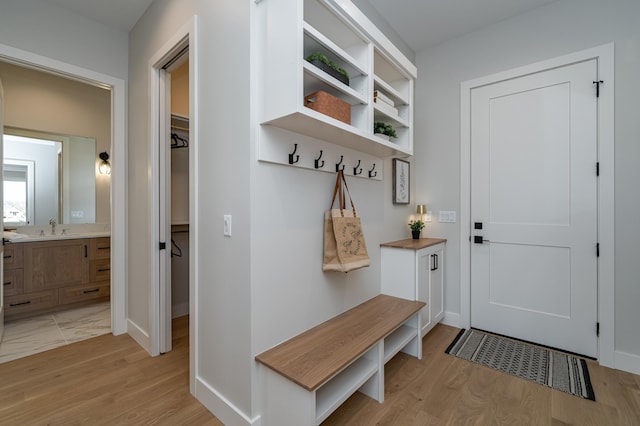 mudroom with light wood-style flooring, baseboards, and a sink