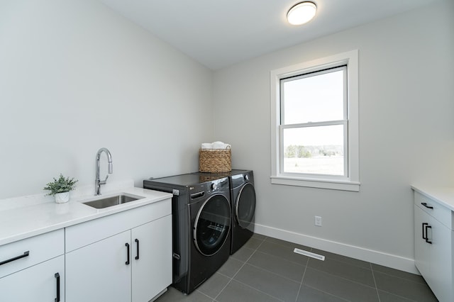 washroom with washing machine and clothes dryer, a sink, baseboards, cabinet space, and dark tile patterned flooring