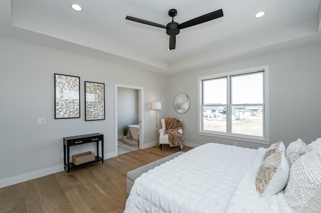 bedroom with recessed lighting, baseboards, a raised ceiling, and wood finished floors