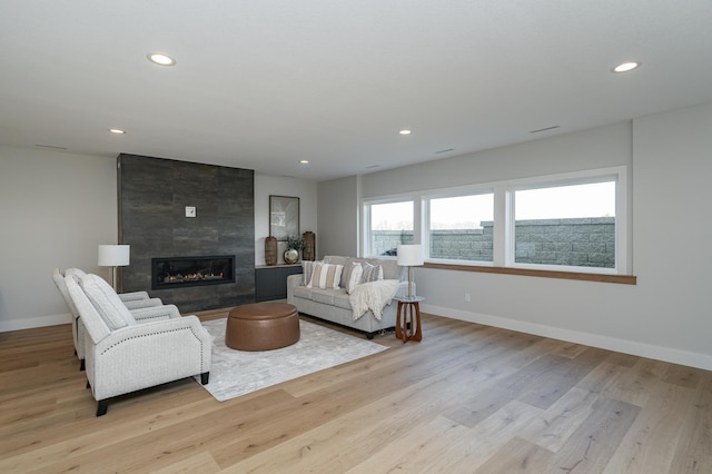 living area featuring recessed lighting, baseboards, light wood-style flooring, and a fireplace