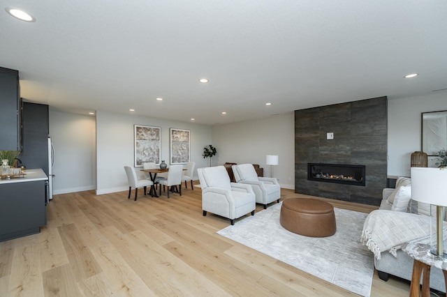 living room featuring recessed lighting, baseboards, light wood-style flooring, and a tiled fireplace