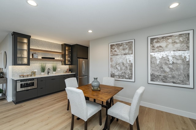 dining area featuring recessed lighting, light wood-style flooring, wet bar, and baseboards