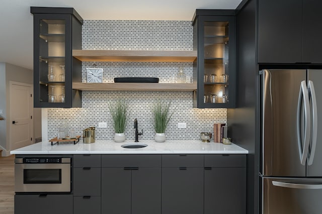 kitchen featuring a sink, open shelves, backsplash, and appliances with stainless steel finishes