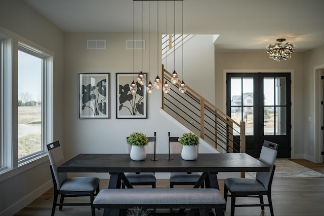 dining area with visible vents, wood finished floors, a chandelier, and stairs