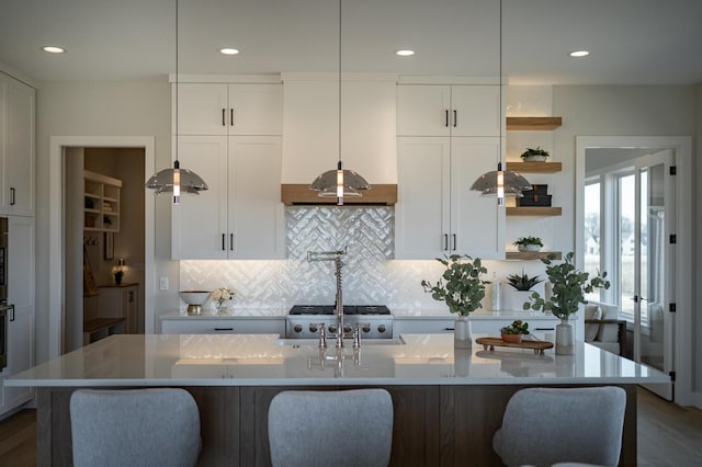 kitchen featuring backsplash, white cabinetry, and custom range hood