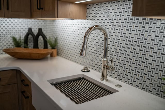 room details featuring a sink, backsplash, and light countertops