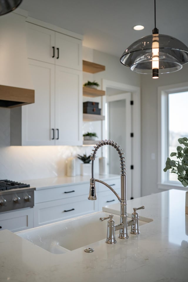 kitchen featuring light stone countertops, open shelves, white cabinets, stainless steel gas stovetop, and decorative light fixtures