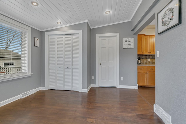 interior space with dark wood-type flooring, a closet, and crown molding