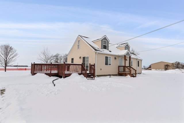 snow covered back of property featuring a deck