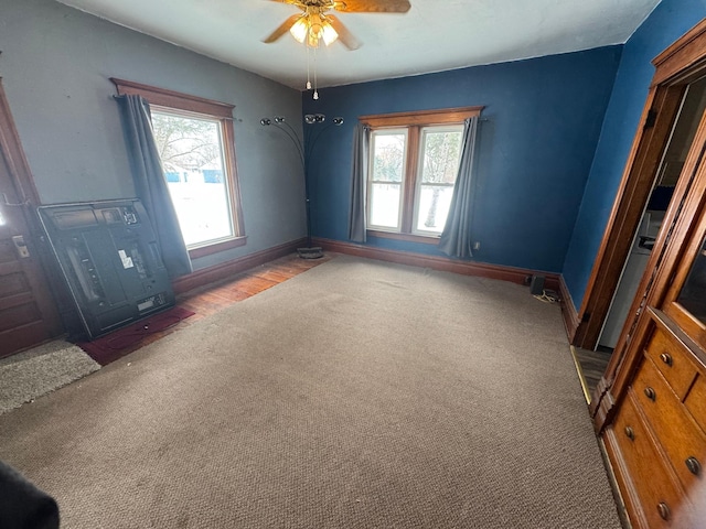 unfurnished room with a wealth of natural light, carpet floors, and ceiling fan