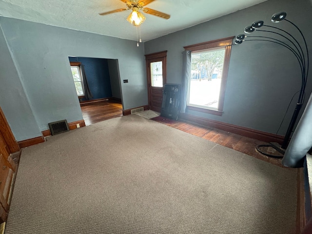 interior space featuring dark colored carpet, a textured ceiling, and ceiling fan