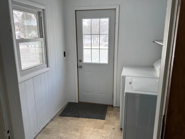 entryway with separate washer and dryer, a wealth of natural light, and wooden walls