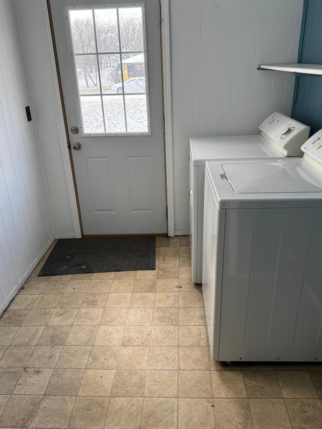 laundry room with washing machine and clothes dryer, wooden walls, and light tile patterned floors