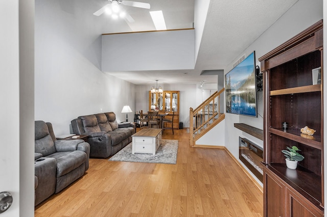 living room with a textured ceiling, light hardwood / wood-style flooring, and ceiling fan with notable chandelier