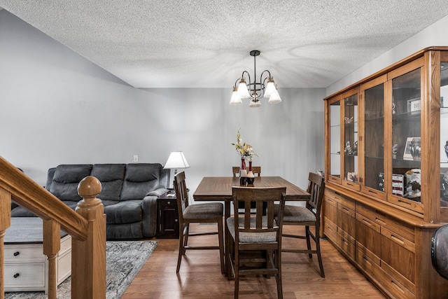 dining area with a notable chandelier, dark hardwood / wood-style flooring, and a textured ceiling