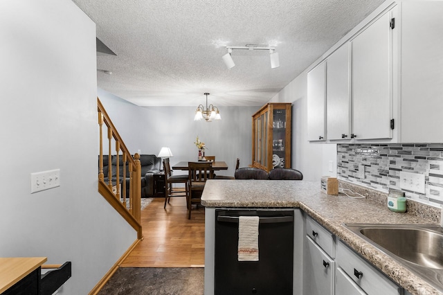 kitchen featuring dark hardwood / wood-style flooring, white cabinets, track lighting, and black dishwasher