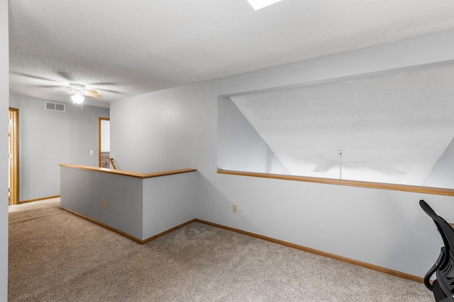 interior space featuring ceiling fan, light colored carpet, and a textured ceiling