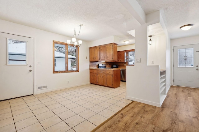 kitchen with stainless steel dishwasher, an inviting chandelier, pendant lighting, and plenty of natural light