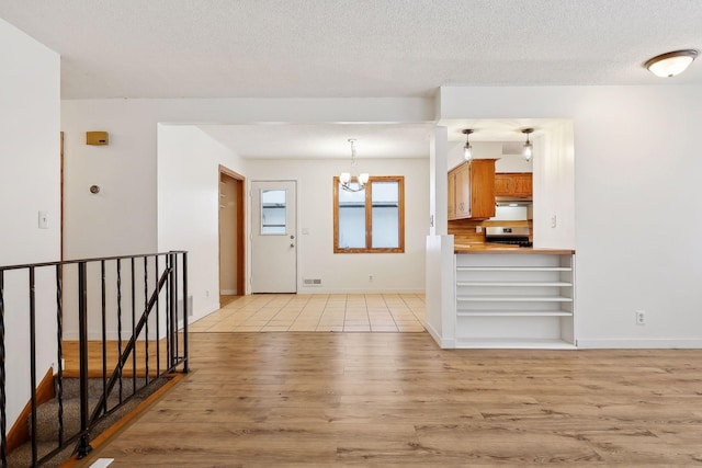 interior space with an inviting chandelier, light hardwood / wood-style floors, and a textured ceiling