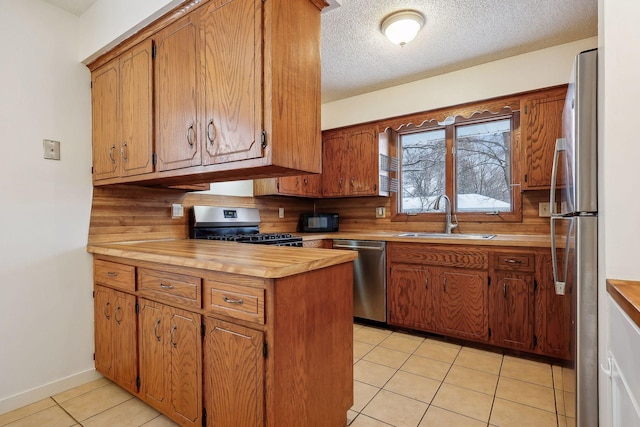 kitchen featuring a textured ceiling, stainless steel appliances, light tile patterned floors, backsplash, and sink