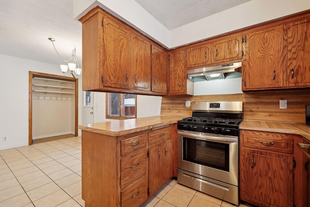 kitchen featuring a textured ceiling, light tile patterned floors, kitchen peninsula, gas range, and a chandelier