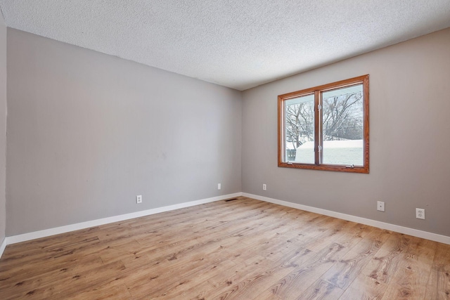 empty room with a textured ceiling and light hardwood / wood-style floors