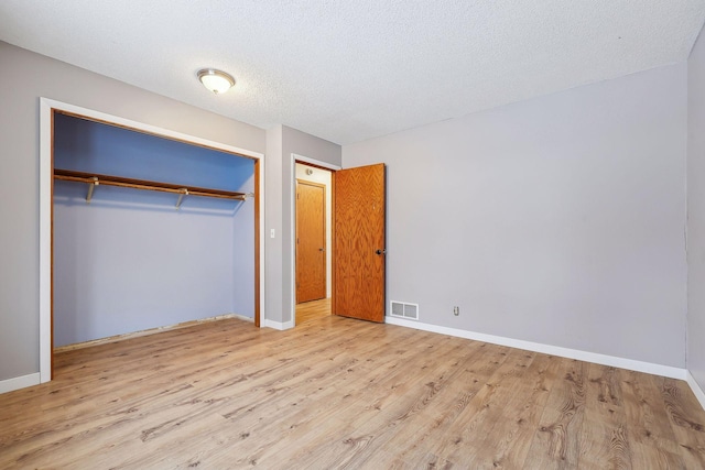 unfurnished bedroom featuring a textured ceiling, light hardwood / wood-style flooring, and a closet