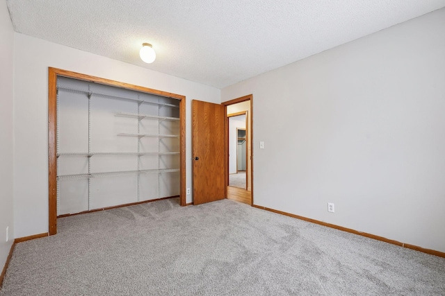 unfurnished bedroom featuring light colored carpet, a closet, and a textured ceiling