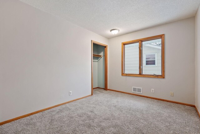 unfurnished bedroom featuring a textured ceiling, a closet, and carpet floors