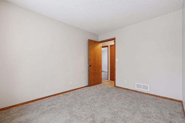 empty room featuring a textured ceiling and carpet