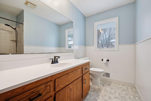 bathroom with tiled shower, vanity, and toilet