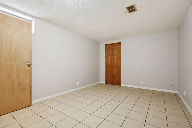 empty room featuring a textured ceiling and light tile patterned floors