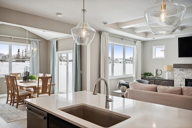 kitchen with dishwasher, sink, light hardwood / wood-style flooring, decorative light fixtures, and a fireplace