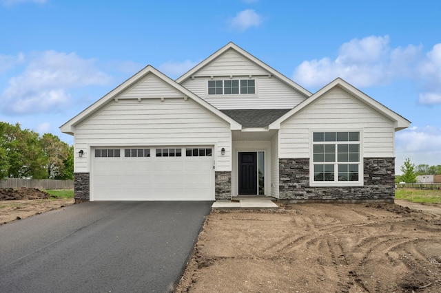 4532 86th St NE, Monticello, MN 55362 - view of front of house featuring stone siding, asphalt driveway, a garage, and a shingled roof