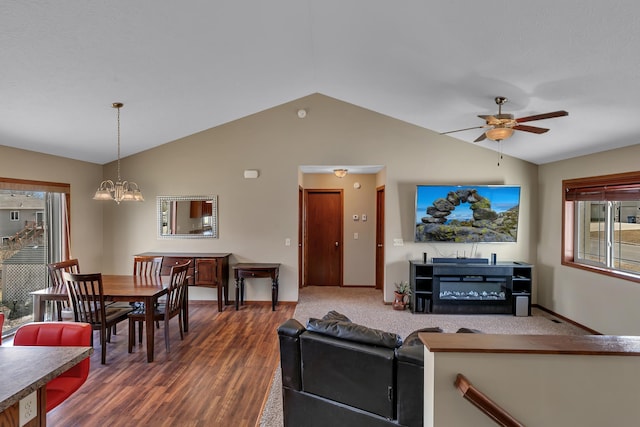 living area with dark wood finished floors, lofted ceiling, ceiling fan with notable chandelier, and baseboards