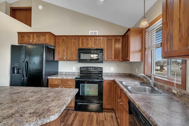 kitchen with visible vents, a sink, black appliances, vaulted ceiling, and brown cabinets