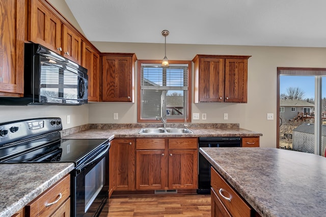 kitchen featuring black appliances, brown cabinets, a wealth of natural light, and a sink