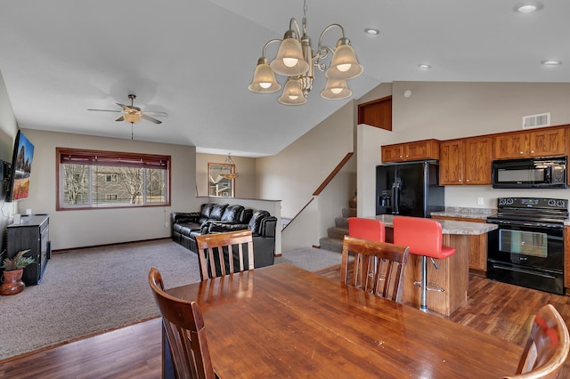 dining area with visible vents, dark wood-style flooring, stairs, ceiling fan with notable chandelier, and dark carpet