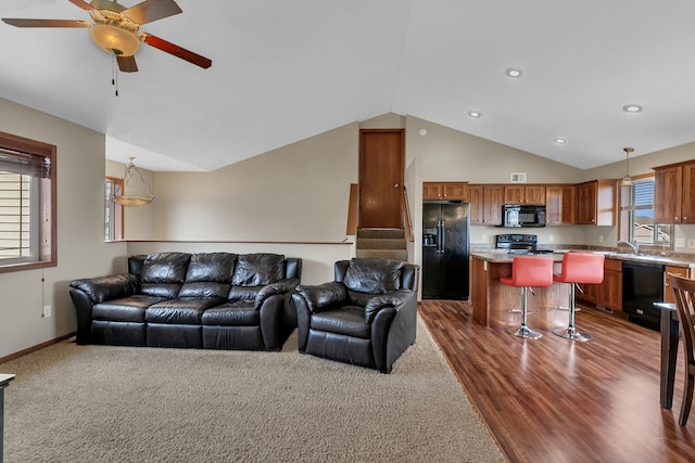 living area with baseboards, plenty of natural light, a ceiling fan, and vaulted ceiling