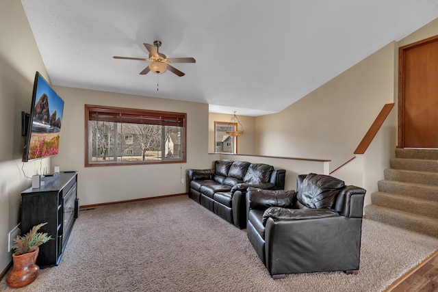 living room featuring stairs, baseboards, ceiling fan, and carpet flooring