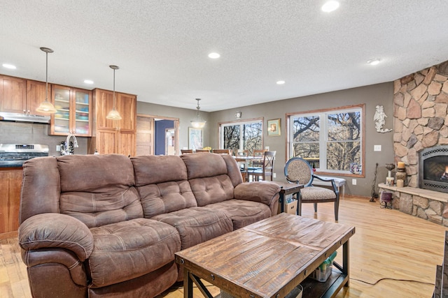 living room with a fireplace, light hardwood / wood-style floors, and a textured ceiling