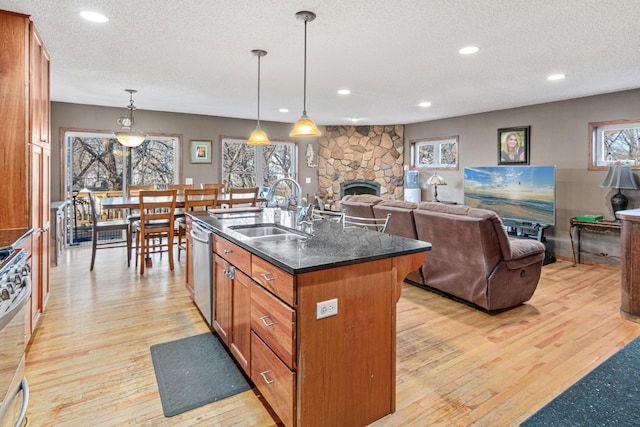 kitchen featuring pendant lighting, a kitchen island with sink, sink, a textured ceiling, and light hardwood / wood-style floors