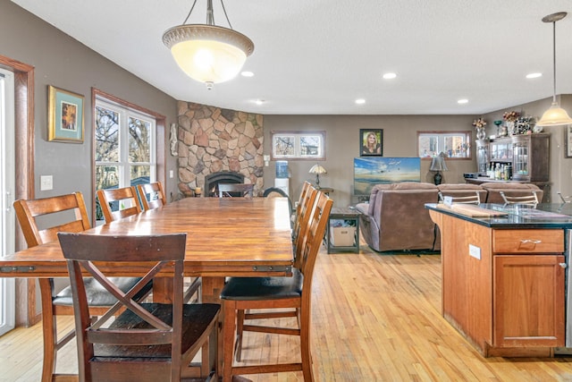 dining area featuring a fireplace, light hardwood / wood-style floors, and a textured ceiling