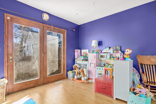 rec room with a textured ceiling and light hardwood / wood-style floors