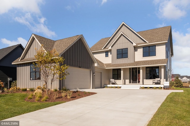 view of front of home with covered porch, a garage, and a front lawn